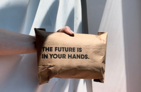 hand holding a brown recycle package with a motivational phrase  in front of a white background 